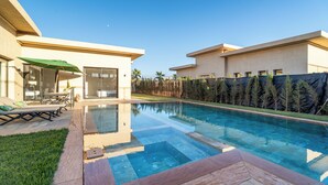 Una casa moderna con piscina, un patio con mobiliario exterior y vistas del paisaje circundante.
