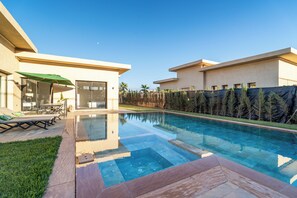 Ein modernes Haus mit Swimmingpool, einer Terrasse mit Gartenmöbeln und Blick auf die umliegende Landschaft.