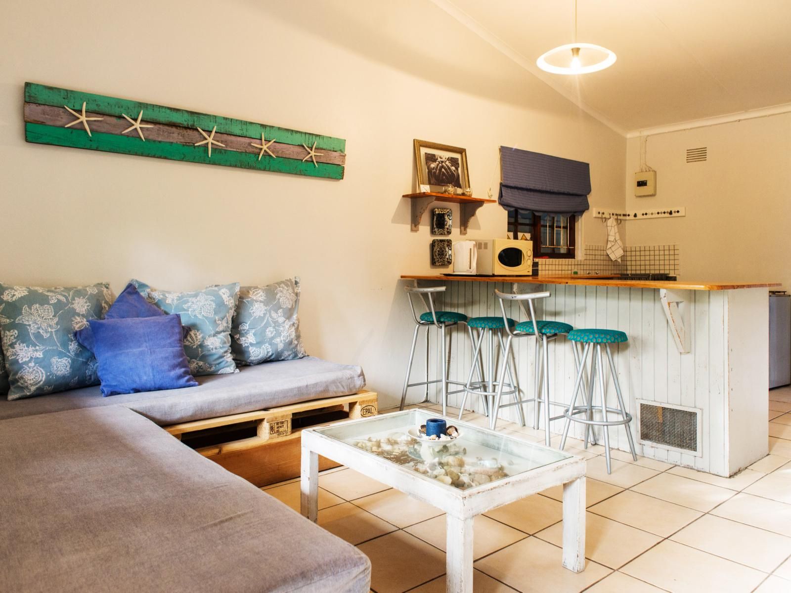 Un espacio habitable compacto con sofá, una mesita de centro, kitchenette y una zona de bar.