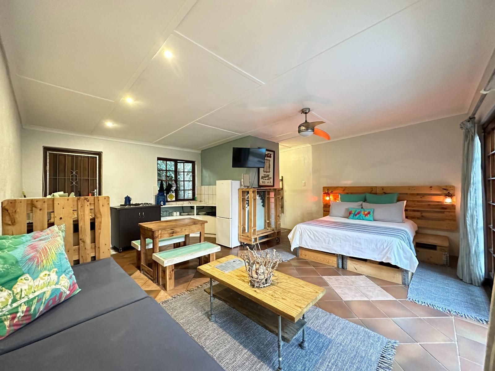 Un espacio habitable compacto con cama, sofá, mesa de madera y kitchenette.