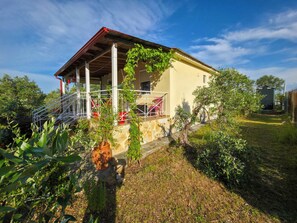 A house with a covered porch, a stone wall, and a garden.