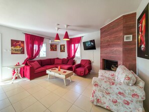 Ein Wohnzimmer mit einer Eckcouch, einem armchair mit floralem Muster, einem Couchtisch und einem flachbildfernseher an der Wand.