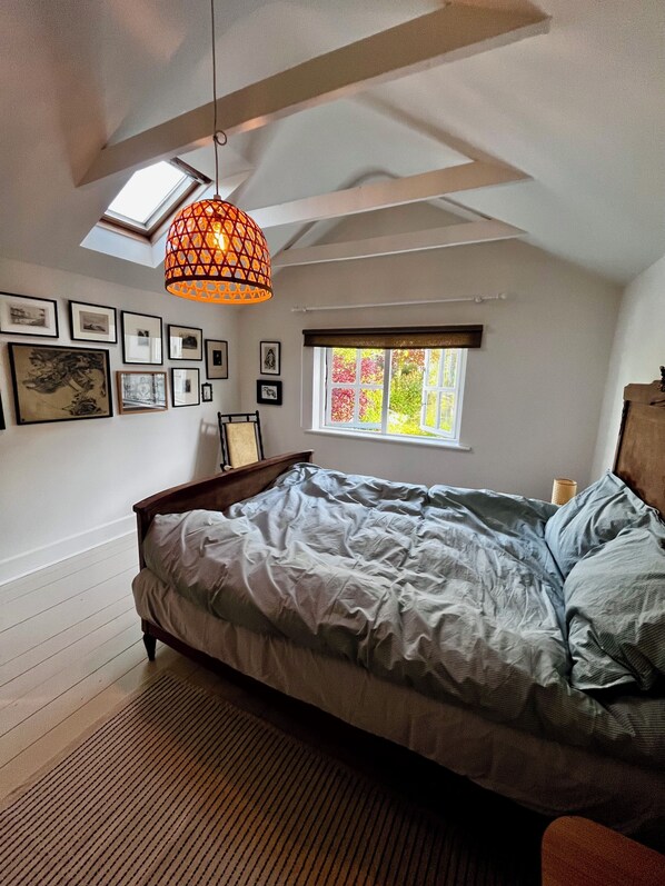 Une chambre à coucher avec un lit, une lucarne, une fenêtre et des tableaux encadrés accrochés au mur.