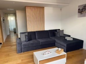 A modern living room with a sectional sofa, a white coffee table, and a wooden partition.
