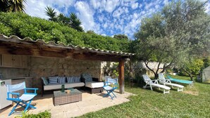 Un patio con mobili da esterno, un muro in pietra e vista su un giardino.