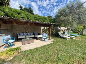 Une terrasse avec des meubles d’extérieur, un mur en pierre et une vue sur un jardin.