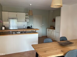 Eine kleine Küche mit weißen Schränken, einer Holz Arbeitsplatte, einer eingebauten Spüle und einer Pendelleuchte.