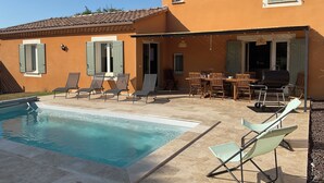 Uma casa com piscina, área de estar ao ar livre e churrasqueira.