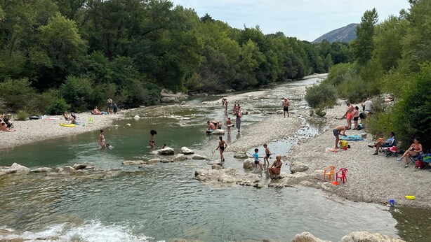 Um rio com pessoas praticando diversas atividades, como natação e pesca.