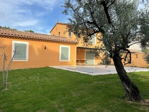 Ein Haus mit Ziegeldach, Rasen und einem Baum.