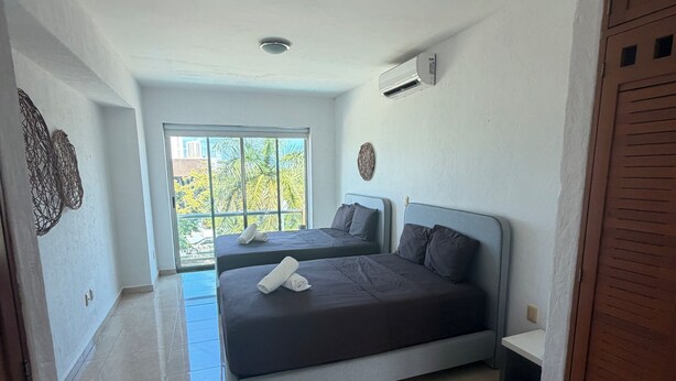 Une chambre avec deux lits, une fenêtre donnant sur un beau paysage et un appareil de climatisation.