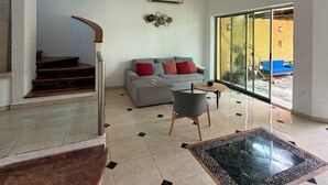 Un salon moderne avec un canapé gris, une table basse et un escalier menant à un autre niveau.