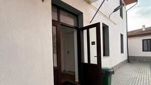 A building entrance with a door, a small window, and a trash bin. - Spacious 2-Room Apartment near Brașov Center | Random Studio | Pet frendly (Brașov)