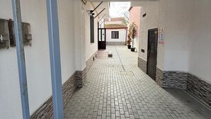 A corridor with a tiled floor, a metal gate, and a door at the end. - Spacious 2-Room Apartment near Brașov Center | Random Studio | Pet frendly (Brașov)