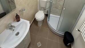 A bathroom with a sink, toilet, and glass shower enclosure. - Spacious 2-Room Apartment near Brașov Center | Random Studio | Pet frendly (Brașov)