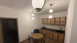 A compact kitchen with wooden cabinets, a round dining table, and pendant lighting. - Spacious 2-Room Apartment near Brașov Center | Random Studio | Pet frendly (Brașov)