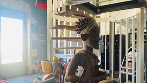 A living room with a large statue, a staircase, and a bookshelf. - Exceptional duplex loft on Marseille's Old Port - Panoramic view (Marseille)