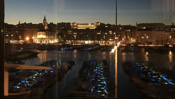 A nighttime view of a cityscape with a river, boats, and illuminated buildings. - Exceptional duplex loft on Marseille's Old Port - Panoramic view (Marseille)
