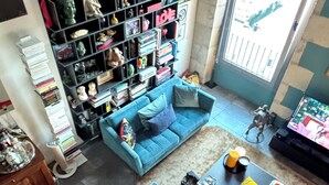 A living room with two blue sofas, a coffee table, a bookshelf filled with books and figurines, and a large window with a view. - Exceptional duplex loft on Marseille's Old Port - Panoramic view (Marseille)