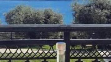 A table with bottles and a can on a balcony overlooking a lake and mountains.