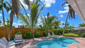 Ein Garten mit Swimmingpool, Liegestühlen und Palmen.