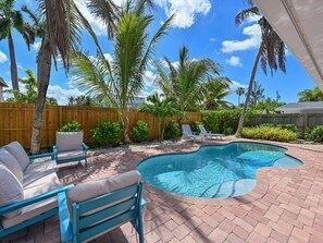 A backyard with a swimming pool, lounge chairs, and palm trees. - White Caps! Short Walk to the Beach~Heated pool (Bradenton Beach)