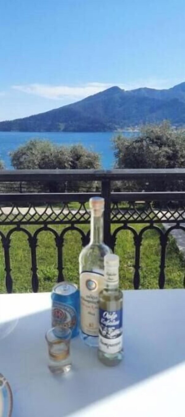A table with bottles and a can on a balcony overlooking a lake and mountains. - Studio Namastekala - Relaxing escape 500 m from the beach (Chrysi Ammoudia)