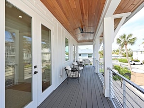 A covered outdoor area with a wooden ceiling, a railing, and a view of the street and palm trees. - White Pearl - Pool/Rooftop/Mini Golf! (Holmes Beach)