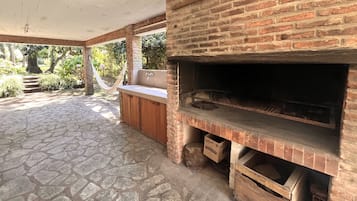 Une terrasse extérieure dotée d’un four en briques, d’un sol en pierre et d’un hamac.