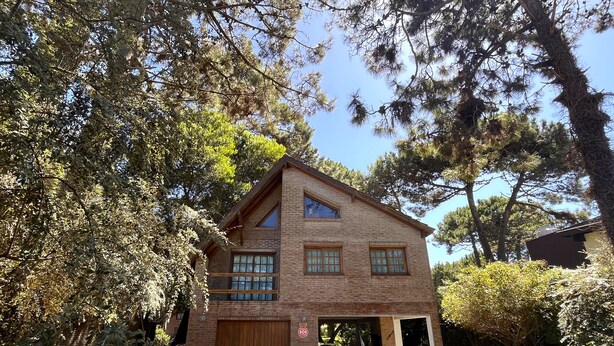 Un bâtiment en briques de deux étages, doté d’un garage, entouré d’arbres et de verdure.