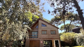 Un bâtiment en briques de deux étages, doté d’un garage, entouré d’arbres et de verdure.
