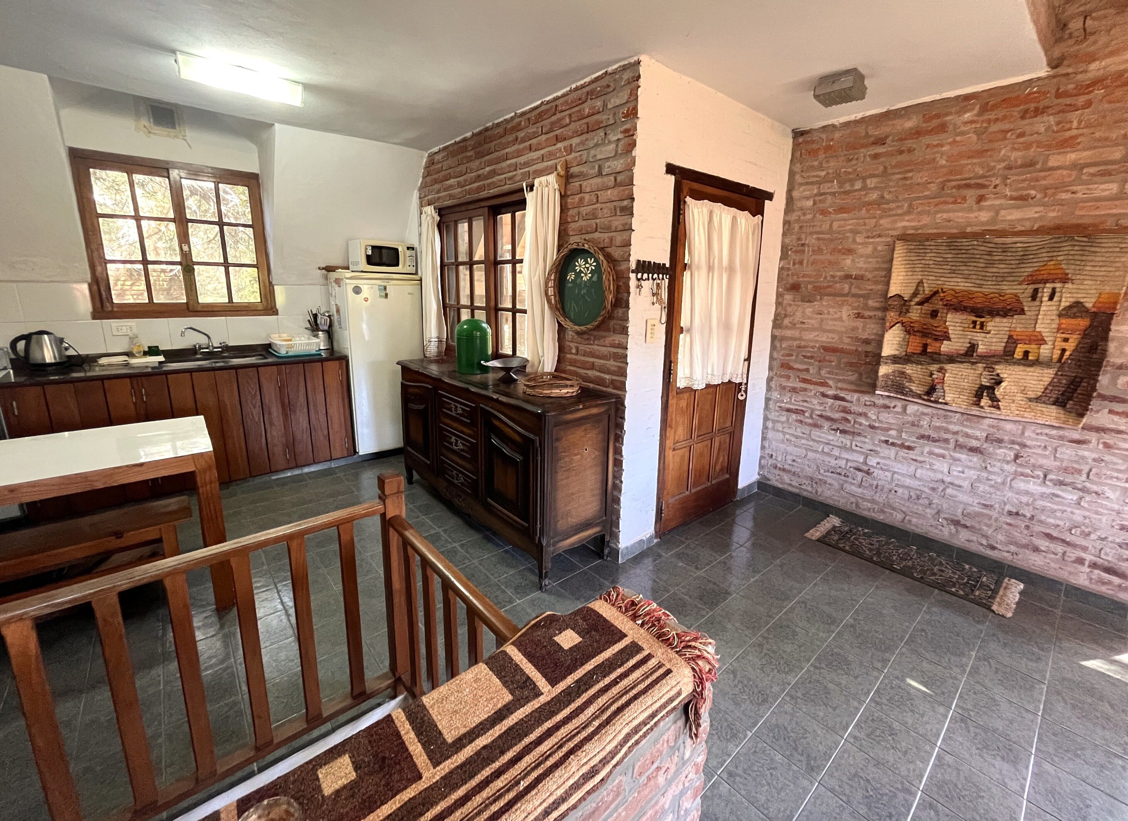 A kitchen with wooden cabinets, a dining table, and a staircase leading to another level.