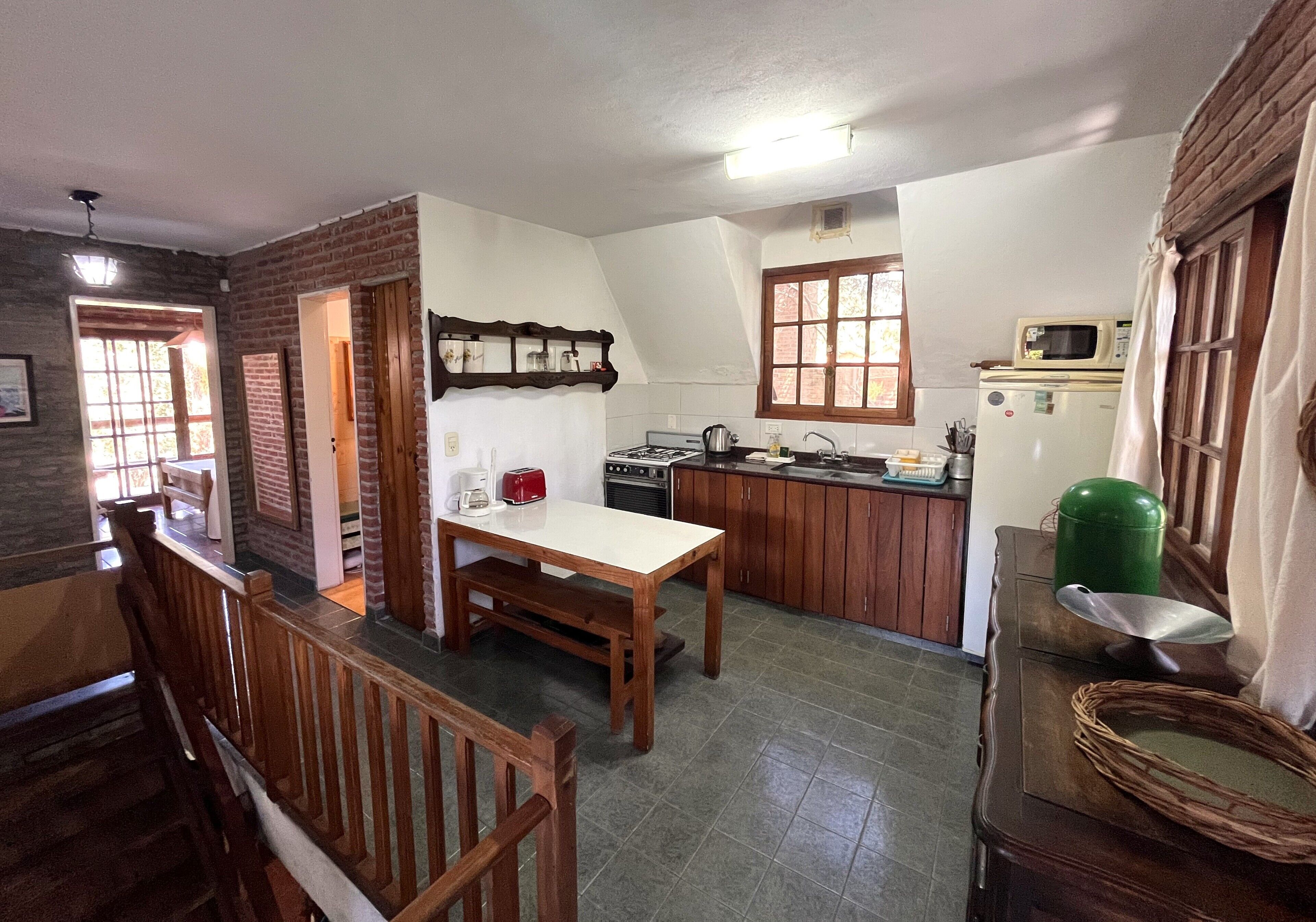 Una cocina con una mesa de comedor, armarios de madera, un microondas y una estufa a gas.