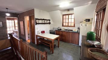 Una cocina con una mesa de comedor, armarios de madera, un microondas y una estufa a gas.