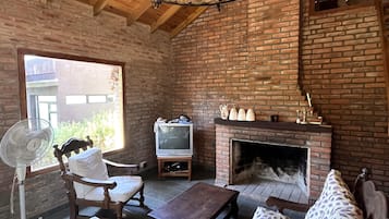 Una habitación acogedora con chimenea de ladrillo, muebles de madera, televisión y candelabro.