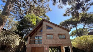 A two-story brick house with a wooden garage door, a covered patio, and a small garden area.