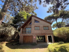 A two-story brick house with a wooden garage door, a covered patio, and a small garden area.