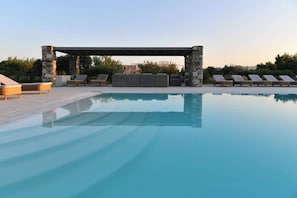 Ein Schwimmbecken mit Liegestühlen und einer Steinstruktur.
