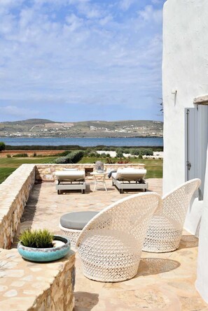 Eine Terrasse mit Gartenmöbeln, einem Blumentopf und Blick auf das Meer und die Landschaft.