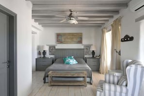Ein Schlafzimmer mit einem Bett, Nachttischen, einem Deckenventilator, einer Bank und einem Stuhl.