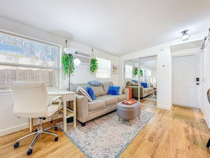 A modern living room with a sofa, a desk, a chair, and a small ottoman. - Cozy studio in fantastic Dunedin with refreshing AC (Dunedin)