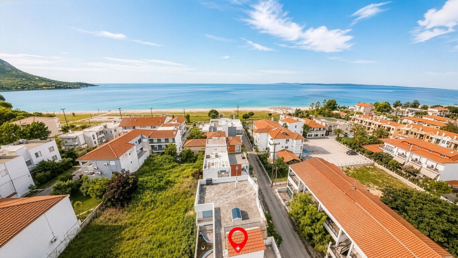 Uma área residencial costeira com edifícios brancos, telhados de telha vermelha e vista para o mar.