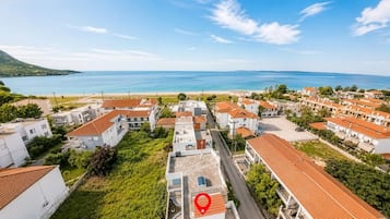 Uma área residencial costeira com edifícios brancos, telhados de telha vermelha e vista para o mar.