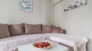 Un saló amb un sofà, una taula de centre amb un bol de flors i dos quadres florals penjats a la paret.