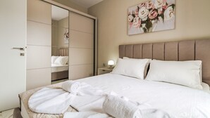 Habitació d'hotel amb un llit, un mirall gran, una petita taula de nit i un quadre de flors a la paret.