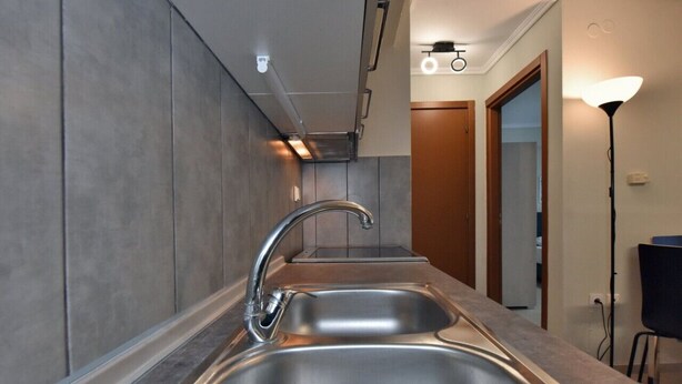 Una cucina moderna con un lavello doppio, piani in acciaio inossidabile e un rubinetto elegante.