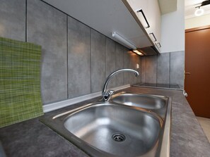 A modern kitchen with stainless steel sinks, a green towel, and a wooden door. - Serenity Apartment by RentalsPro - Nea Moudania (Nea Moudania)
