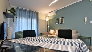 Una moderna camera d'hotel con un tavolo da pranzo in vetro, una poltrona, una TV e una lampada.