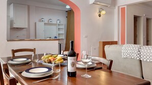 A dining area with a wooden table set for two, a bottle of wine, and a fruit bowl. - Casa del Custode: Via degli Dei – Mugello Circuit (Tagliaferro)