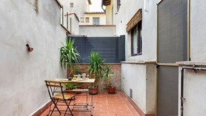 A small outdoor patio with a table and chairs, surrounded by potted plants and a tiled floor. - Casa del Custode: Via degli Dei – Mugello Circuit (Tagliaferro)